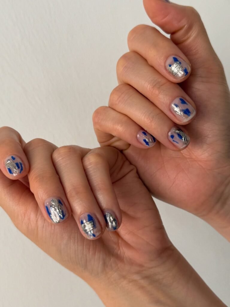 Short abstract nails with hand-painted blue and silver chrome details on a nude base