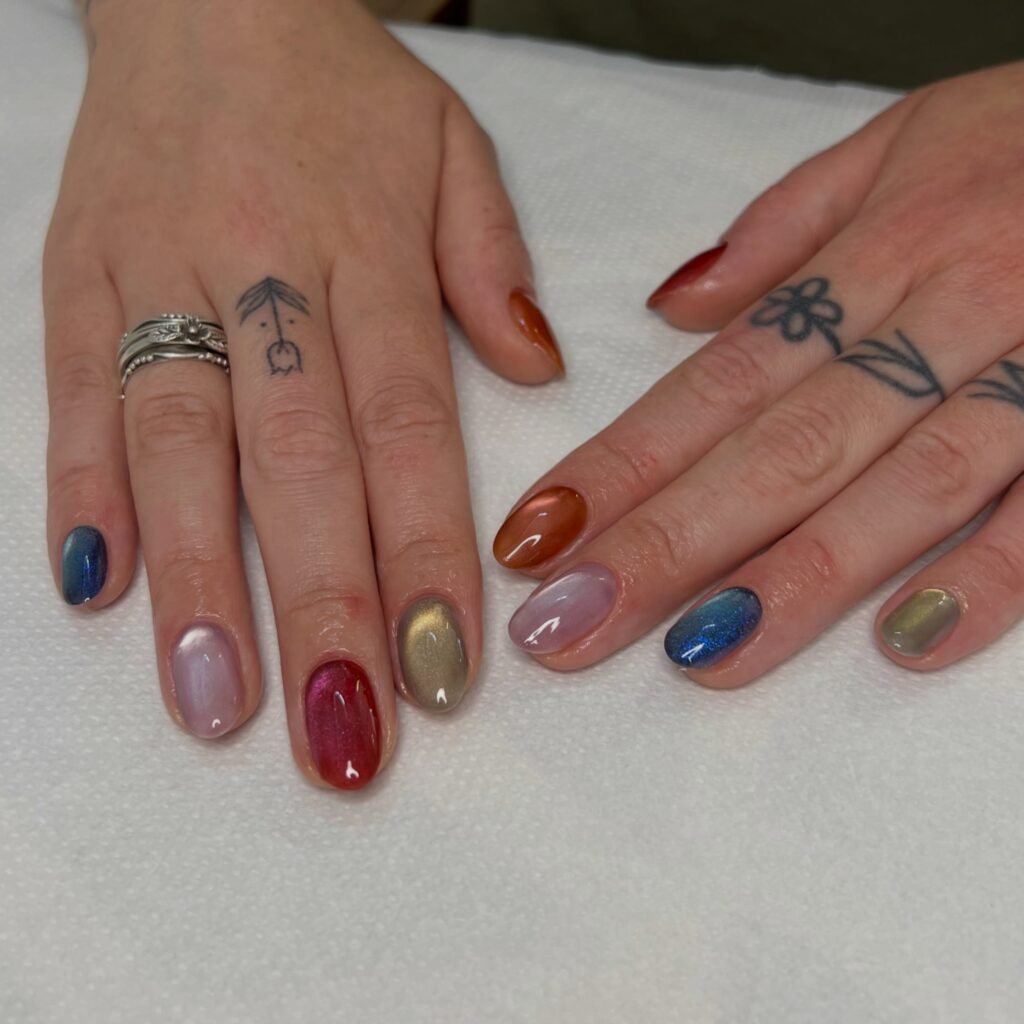 Short cat-eye nails in a mix of pink, red, blue, gold and orange