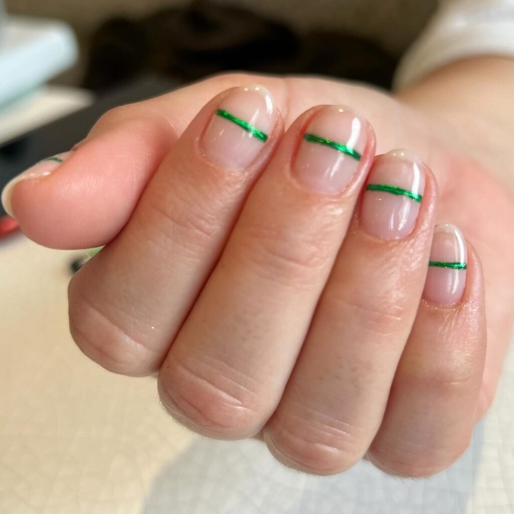 Short floating french nails with a thin metallic green line above a natural glossy base
