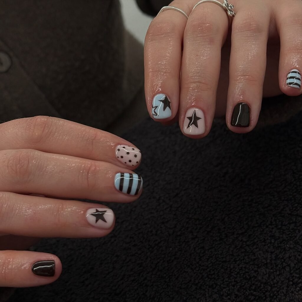 Short nails with a mix of black stars, stripes and polka dots in blue, black and white
