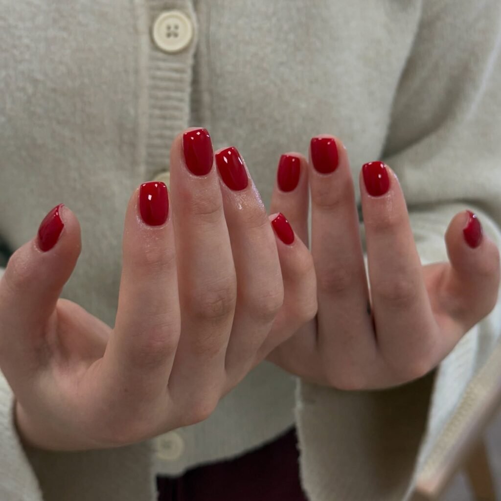 Short glossy red nails in a squoval shape, a classic red manicure on natural nails