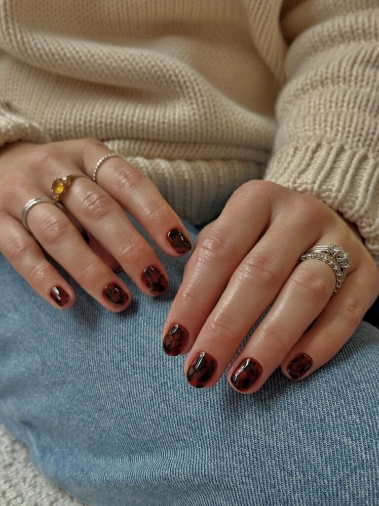 Short tortoiseshell nails with a glossy cherry-burgundy base and black brown tortie pattern