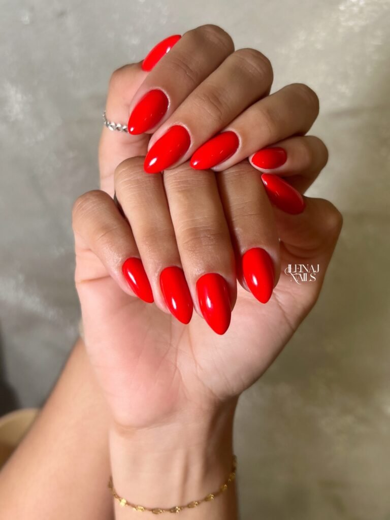 bright scarlet red nails on long almond shape, glossy November manicure